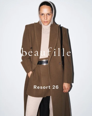 Model Laura Rylands wearing a tailored brown coat, mini skirt, and cream turtleneck against a white background for Beaufille Resort 26.
