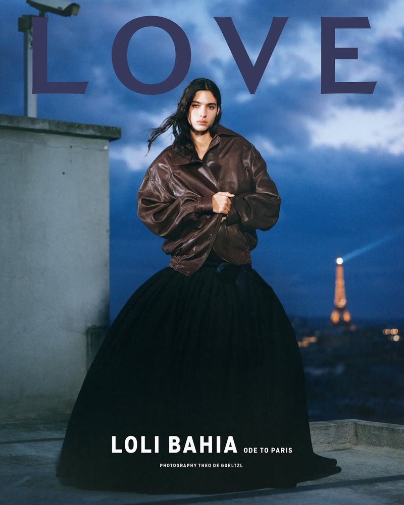 Fashion editorial photo on a rooftop with a model in a brown jacket and black dress, with the Eiffel Tower lit in the background.