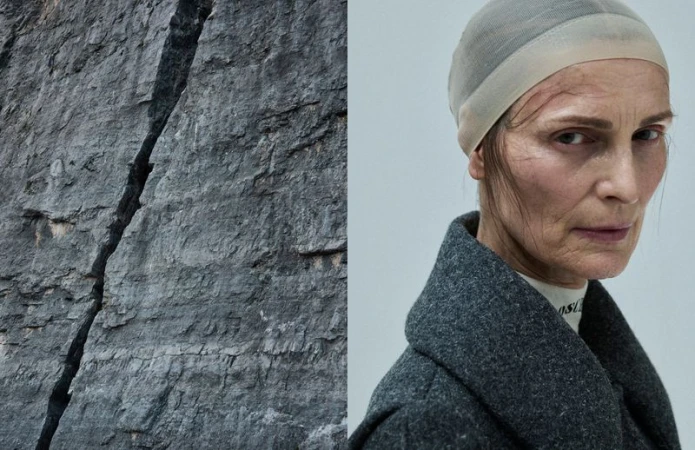 Striking image juxtaposing a mature woman in a gray coat and head covering against a rugged rock face, creating a compelling contrast.