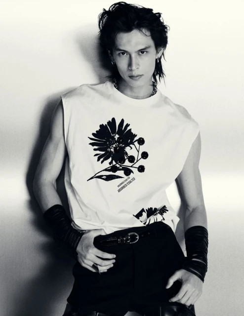 Model Yang Hao in a graphic sleeveless white top and black wristbands posing against a studio backdrop in black and white.