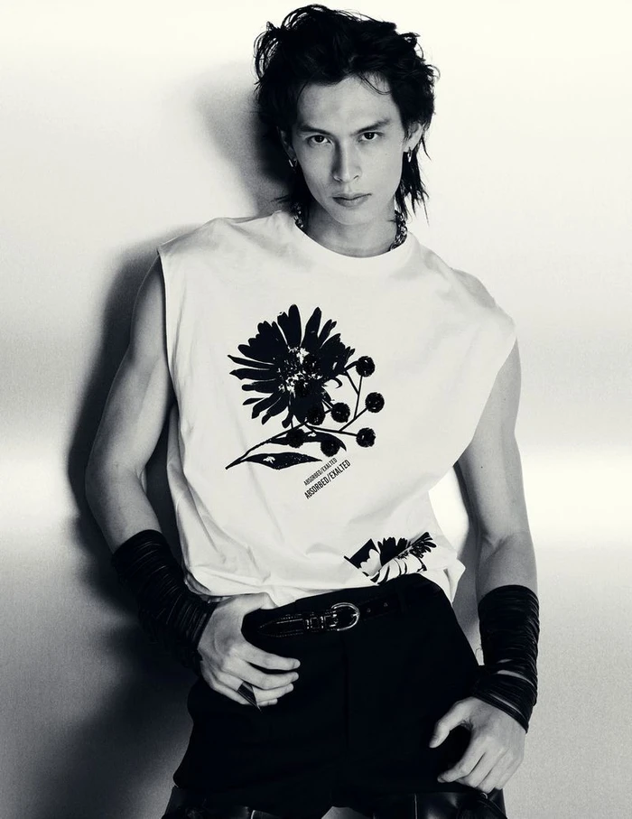 Model Yang Hao in a graphic sleeveless white top and black wristbands posing against a studio backdrop in black and white.