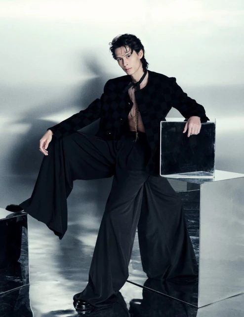 Model Yang Hao in black patterned jacket and wide trousers posing on mirrored cube for L'Officiel Malaysia