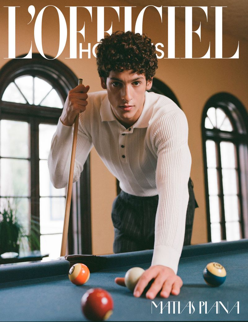 Man poses with a pool cue and several billiard balls in an indoor setting, featured on a magazine cover.
