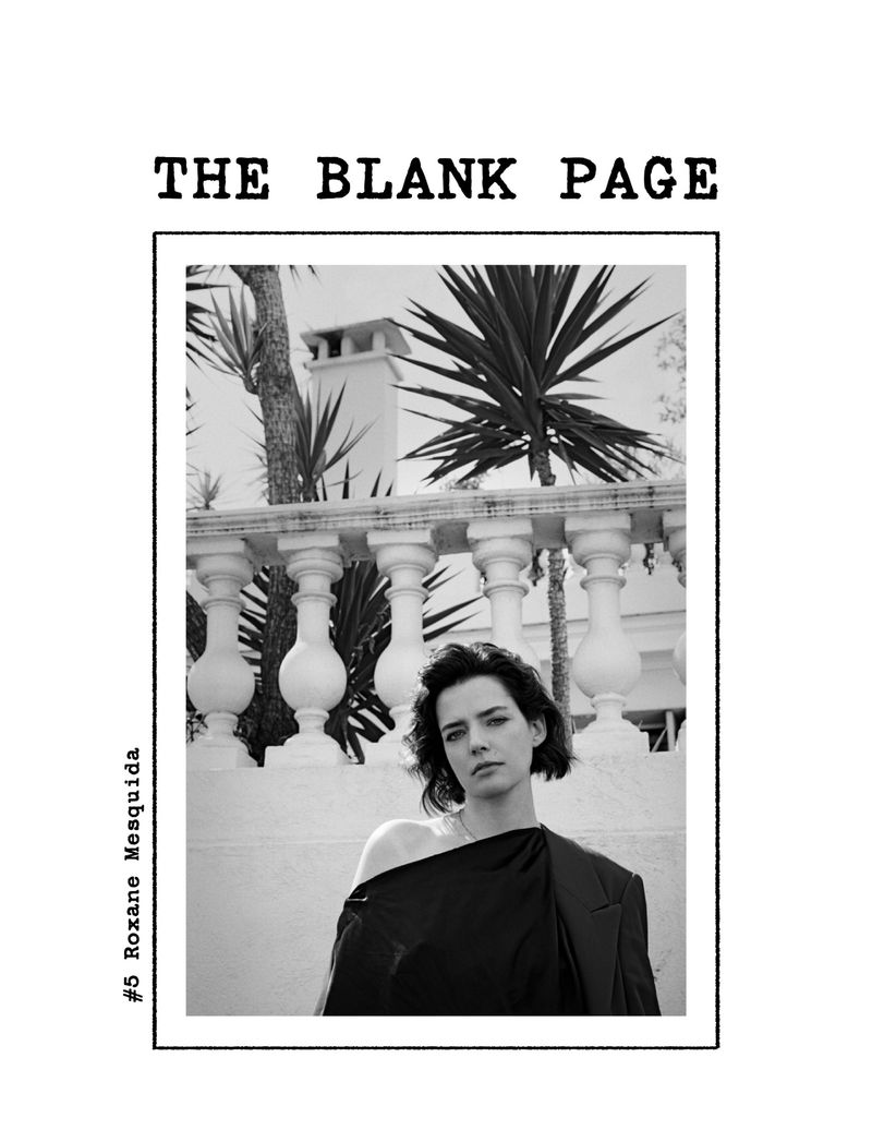 Black and white magazine cover with a woman in draped black fabric, posing outdoors with a white balustrade and palm trees.