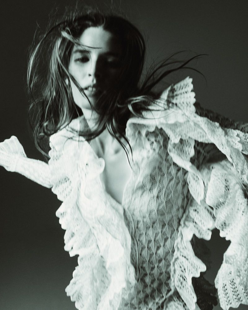 Portrait of a fair-skinned adult female wearing a lacy white top, set against a neutral background with prominent shadows and soft studio lighting.