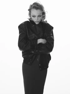 Model with dark winged eyeliner wearing a black leather jacket against a seamless white background