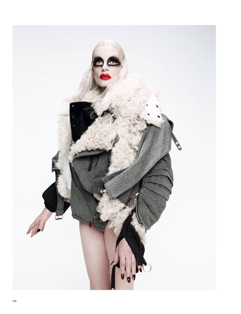 Fashion photo featuring a model with pale skin and dramatic makeup wearing a textured jacket against a bright, neutral background in a studio.