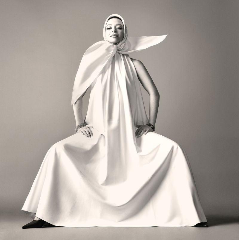 Mikey Madison seated in a voluminous white draped gown with matching headscarf against a studio backdrop for Vogue Italia.