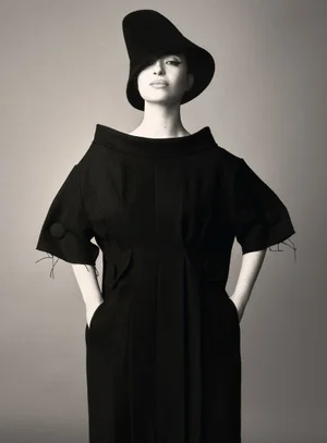 Portrait of Mikey Madison wearing a structured black dress and asymmetric hat against a grey backdrop for Vogue Italia.