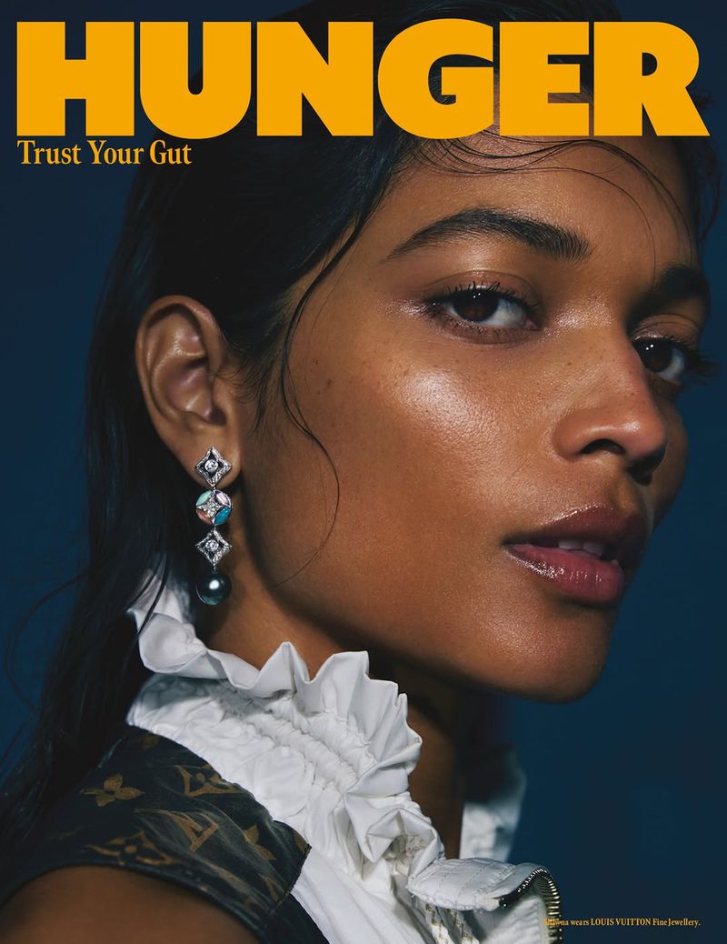 Close-up magazine cover featuring a model with a wet hair look, glossy lips, pearl earring, white ruffled top, and Louis Vuitton jacket.