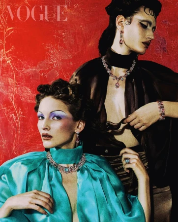 Editorial fashion portrait of two models wearing elegant gowns and jewelry, posing against a textured red background with the Vogue logo.
