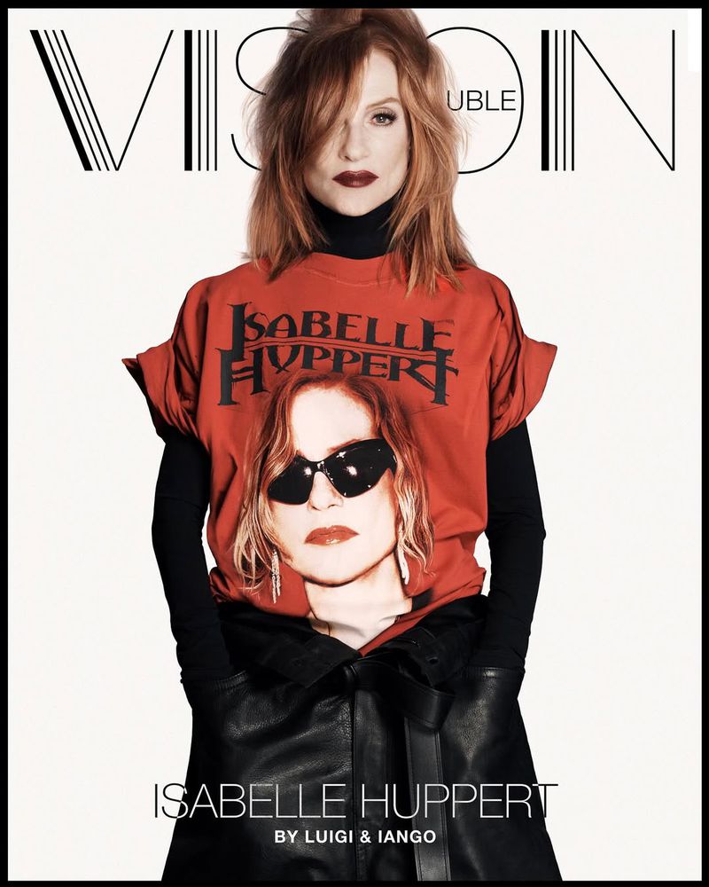Isabelle Huppert poses for a magazine cover wearing a T-shirt with her image on it, paired with black leather-like pants and black turtleneck.