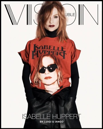 Isabelle Huppert poses for a magazine cover wearing a T-shirt with her image on it, paired with black leather-like pants and black turtleneck.