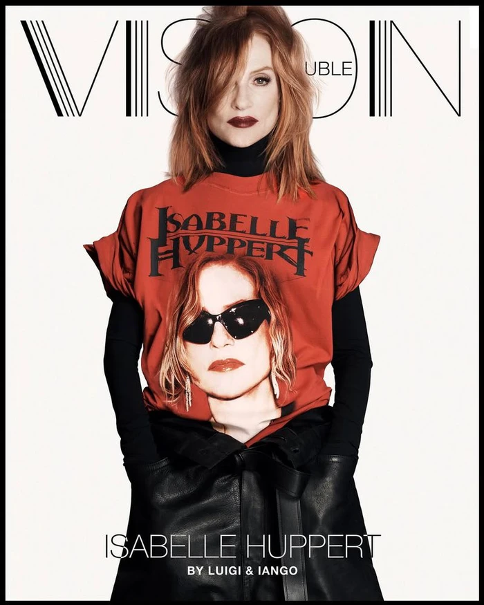 Isabelle Huppert wearing a red graphic t-shirt over black layers and a dark leather skirt against a white studio background.