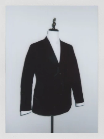 Dark blazer on a mannequin with white shirt, set against a plain white backdrop in a studio setting, fashion or clothing concept.