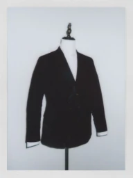 Tailored black suit jacket displayed on a white mannequin torso against a neutral studio backdrop.