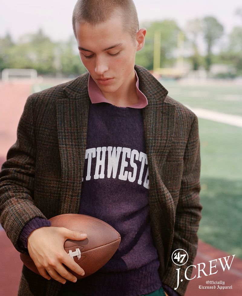 Young man in collegiate sweater and brown jacket holds football on sports field for J. Crew apparel advertisement, autumn fashion.