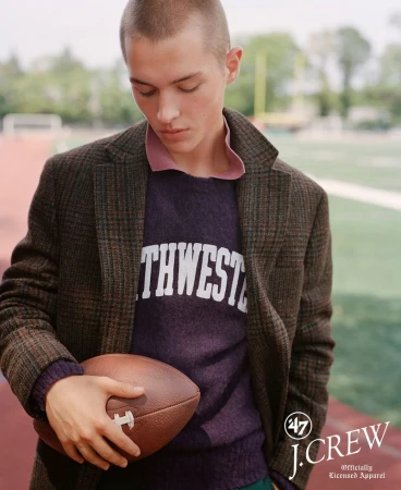 Young man in collegiate sweater and brown jacket holds football on sports field for J. Crew apparel advertisement, autumn fashion.