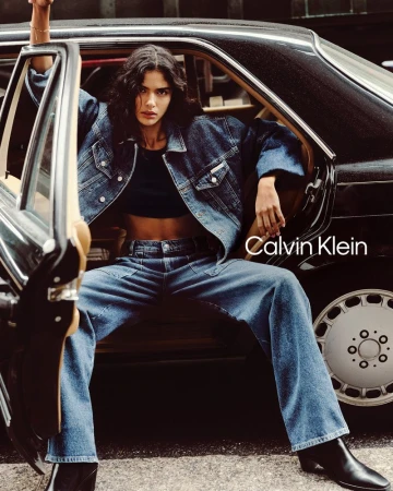 Denim fashion shoot featuring an adult female model in a classic car, showcasing denim jacket, jeans, and black ankle boots for Calvin Klein.