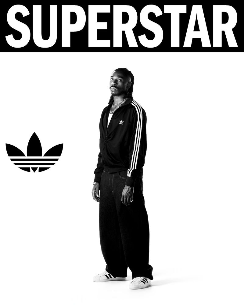 Black and white portrait of a male model wearing an Adidas tracksuit with Superstar text above the subject and the Adidas logo to the left.