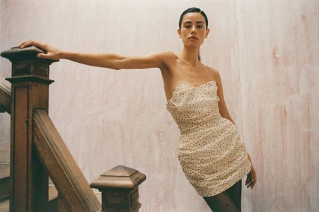 Model in strapless dotted mini dress leaning on a wooden staircase for Vogue Polska New Look editorial