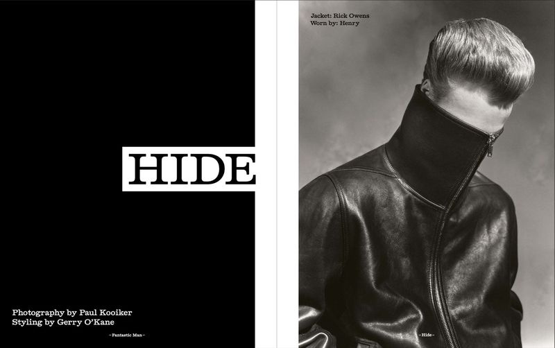Fashion editorial shot of a man wearing a black leather jacket with the jacket collar pulled up, shot in black and white.