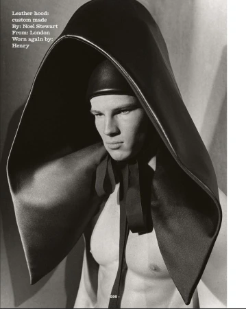 Monochromatic portrait of a muscular man wearing a custom-made black leather hood, shot indoors with studio lighting and subtle post-production.