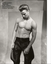 Shirtless male model with pompadour hair wearing black leather jodhpur pants and a buckle belt in a studio setting.