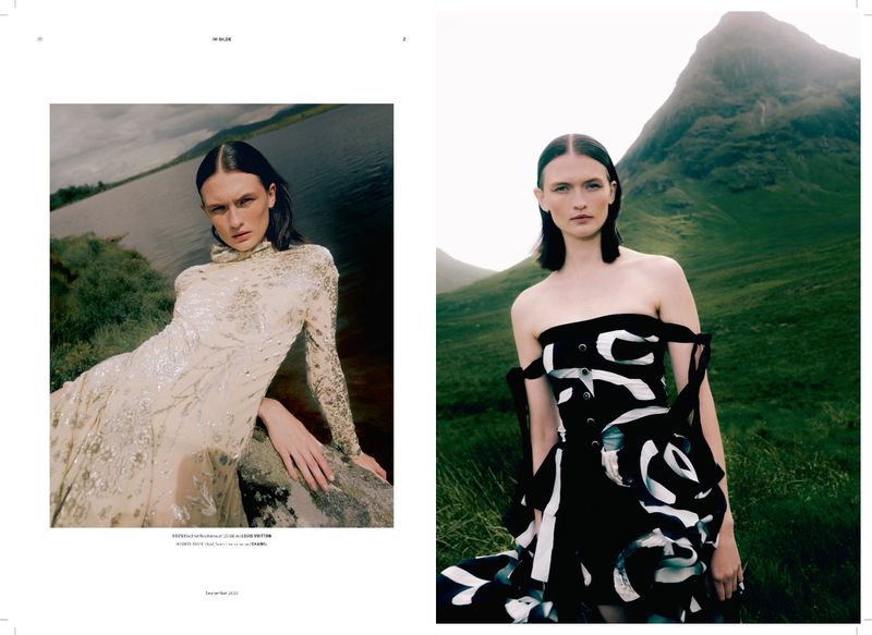 Fashion editorial featuring a model in a couture dress, posing in a natural landscape with mountains, against a cloudy sky.