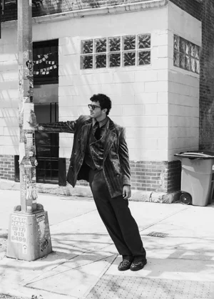 Man leaning against a street pole wearing a pinstripe suit jacket and trousers for an editorial by Anka Garbowska.