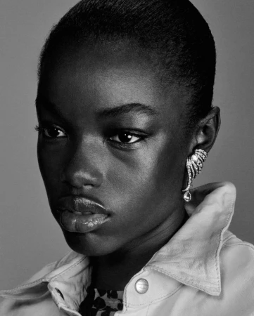 Black and white close-up portrait of model Assa Sidibe wearing a sparkling crystal ear cuff and collared jacket.