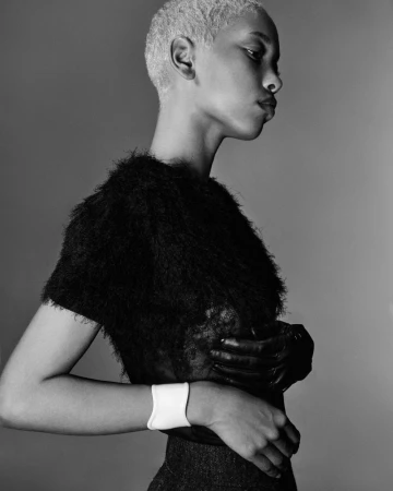 Monochrome portrait of a Black woman in a textured top, side profile view against a solid gray background in a photo studio.