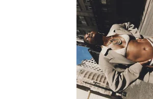 Model posing in an open beige blazer and white knit crop top against a city street backdrop.