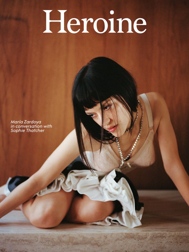 Magazine cover featuring a woman kneeling, wearing a bra top and tutu skirt against a brown backdrop, featuring the text 'Heroine'.