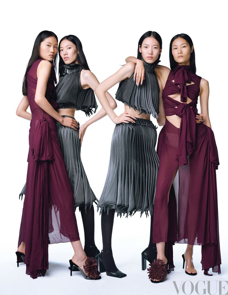Four fashion models in coordinating burgundy and grey outfits, posing together against a white backdrop for a studio photoshoot.
