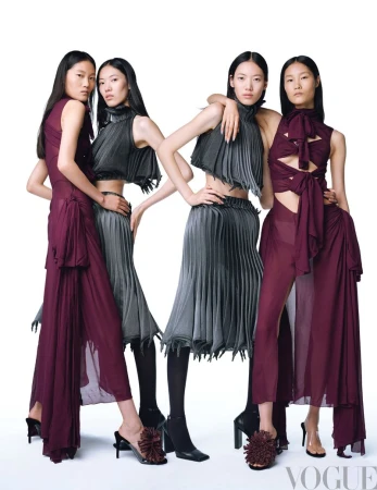 Four fashion models in coordinating burgundy and grey outfits, posing together against a white backdrop for a studio photoshoot.