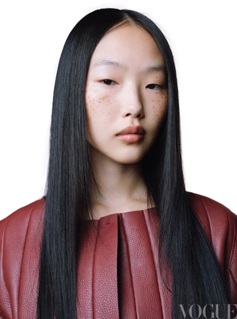 Close-up shot of an Asian female model with long black hair wearing a red leather jacket against a clean white background.