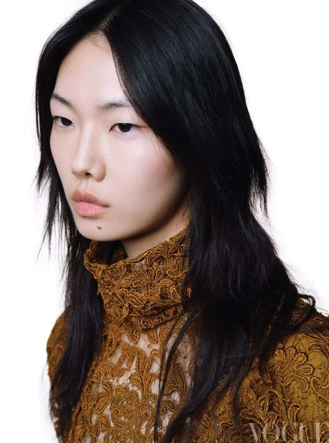 Asian woman in a lace top with black hair poses in a studio portrait with a white background and soft lighting, showcasing fashion and beauty.