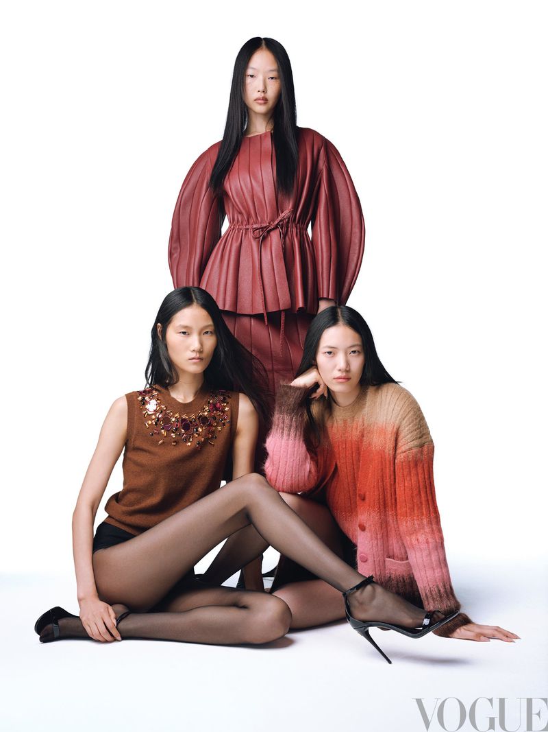 Three Asian female fashion models pose indoors against a white background, showcasing a textured leather top, knitwear and black hosiery.