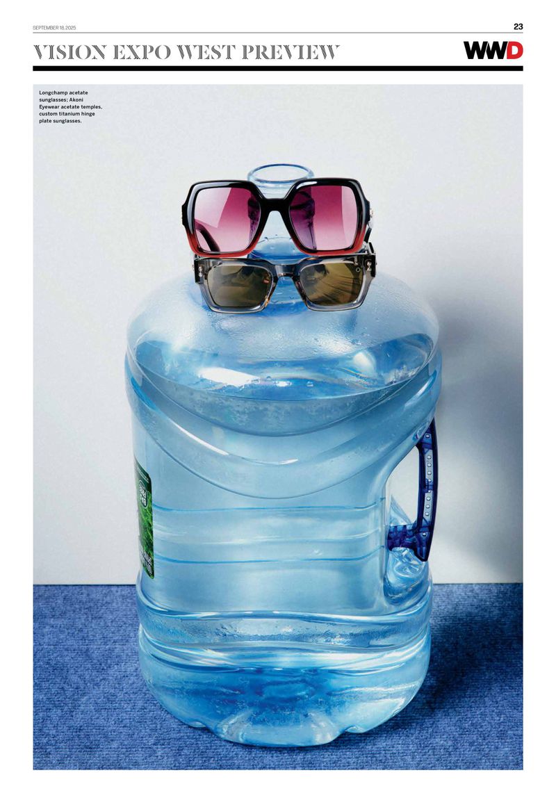 Two pairs of sunglasses are stacked on top of a large, clear water bottle against a light-colored backdrop with a blue textured surface.