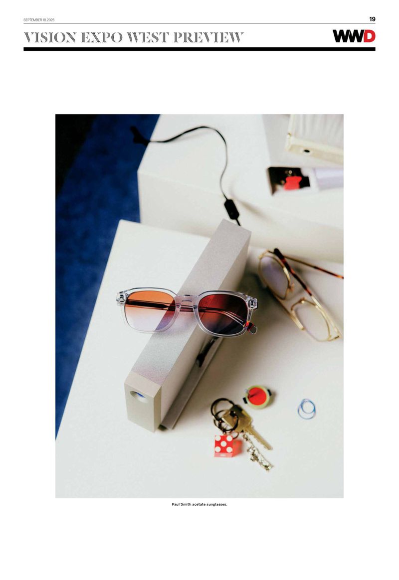 Still life studio shot of Paul Smith available sunglasses with keys and other accessories in a minimalist style on white surface.