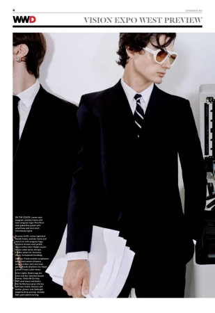 Two men in dark suits, one wearing sunglasses, standing next to a printer. Fashion editorial, modern vintage style, studio lighting.