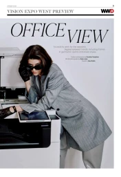 Model in grey blazer leaning on a copy machine wearing sunglasses and dark gloves against white backdrop
