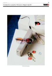 Clear acetate sunglasses with orange-tinted lenses resting on a block with keys, dice keychain, and gold eyeglasses on a desk.