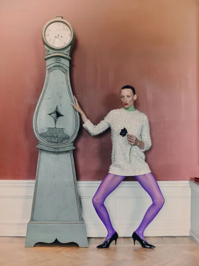 Model Maggie Maurer posing beside a tall grandfather clock for Vogue Czechoslovakia editorial Milovaná