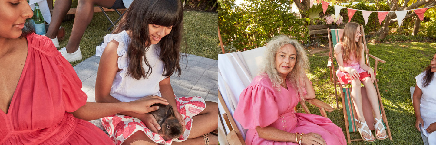 Outdoor gathering of women and a girl in dresses enjoying time together on a sunny day with a pet rabbit on a patterned blanket.
