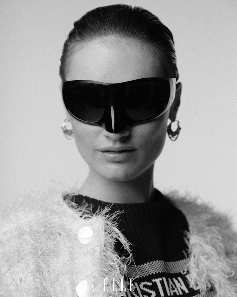 Model wearing oversized black sunglasses and a textured white garment against a plain background for Elle China.