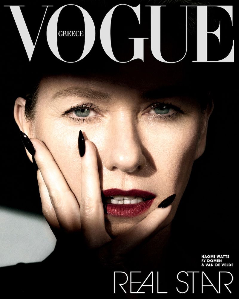 Vogue Greece magazine cover featuring a close-up portrait of Naomi Watts with dark red lipstick and long black nails, on a black background.