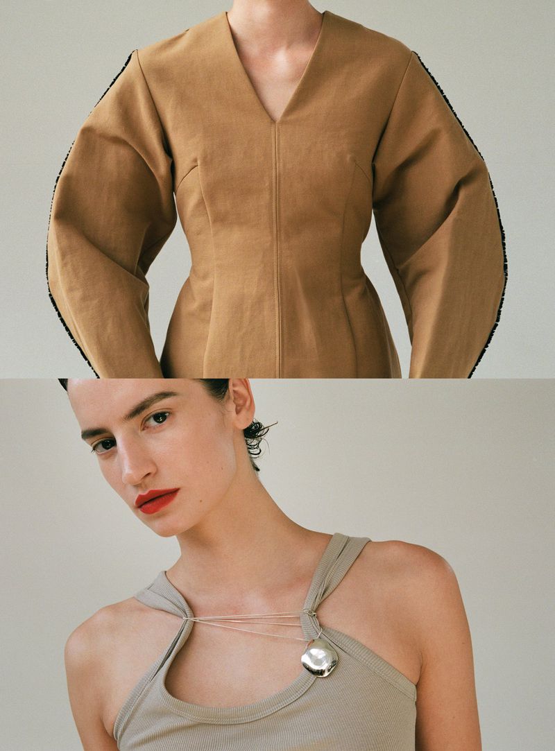 Fashion portrait of a young fair-skinned woman wearing a tan dress with wide sleeves and a light beige tank top with a silver medallion.