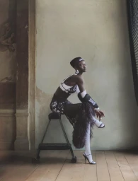 Model Nyakong Chan seated on a rolling stool wearing black and white performance-inspired fashion for Numero France by Rowan Papier